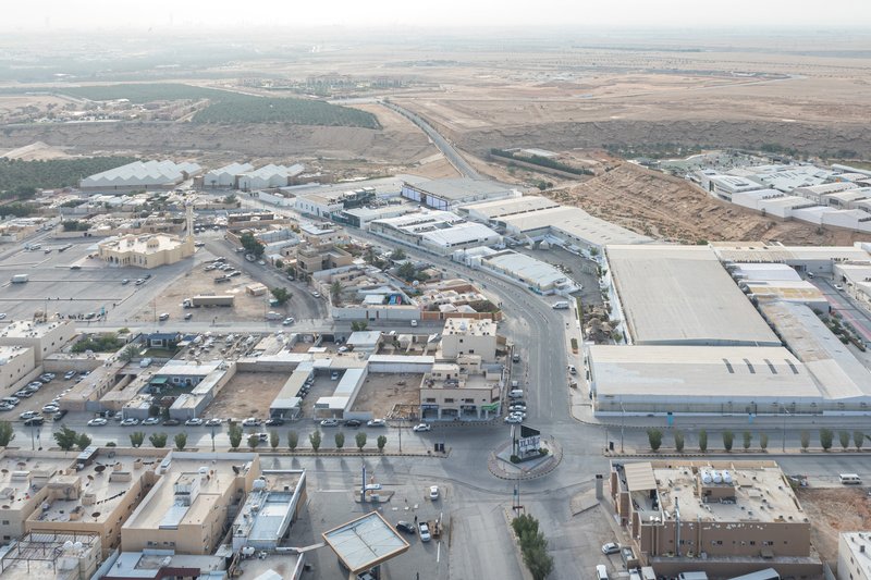 Aerial view of industrial compound with metal-roofed warehouses beside roads and arid landscape