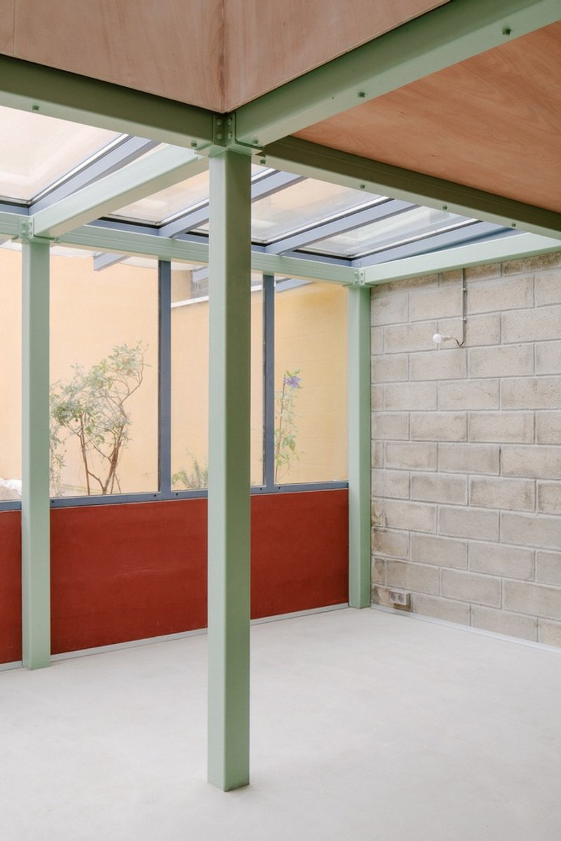 Interior corner showing green steel frame with skylights and red half-height partition wall