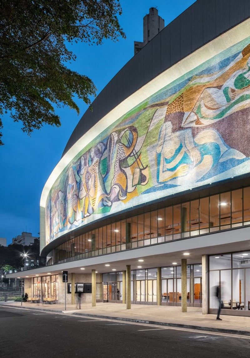 Close-up of the curved facade showing the mosaic frieze above the glazed colonnade at dusk