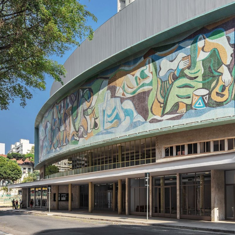 Close view of the curving mosaic mural depicting figures and musical instruments under clear sky