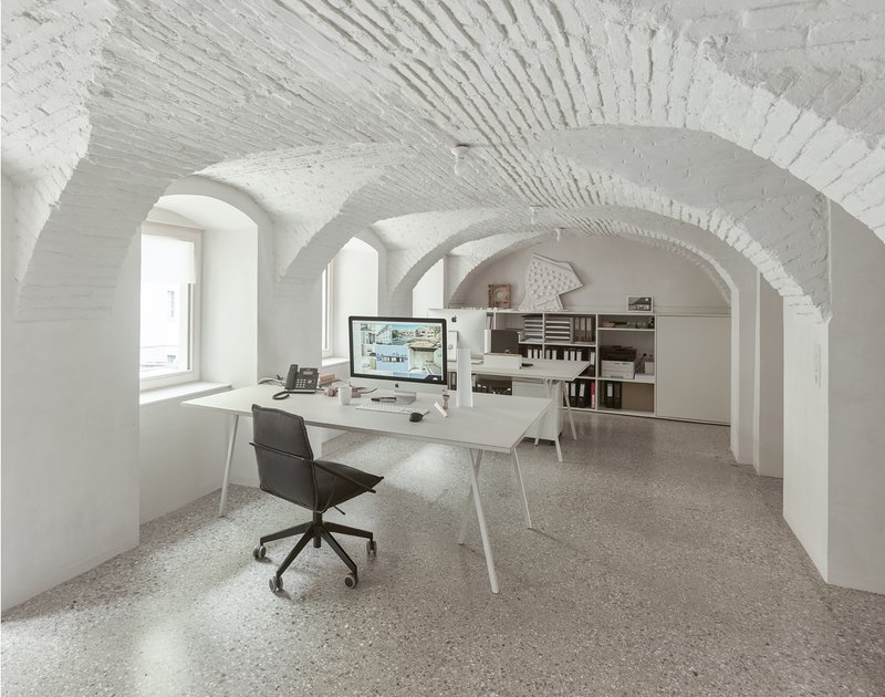 White vaulted brick ceiling with radiating ribs above an office workspace with terrazzo flooring