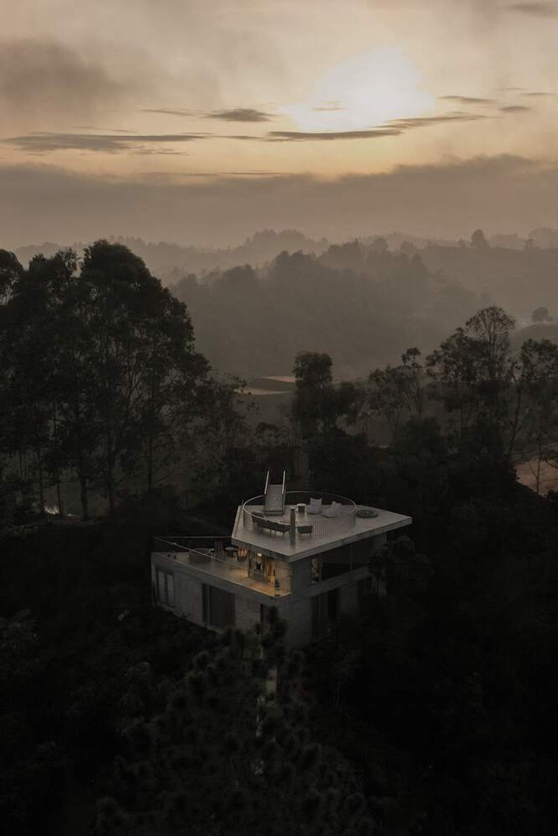 Aerial view of flat roof terrace nestled among forested hills at dawn