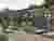 This architectural image depicts a cemetery with a man pulling a cart along a paved pathway. The cem