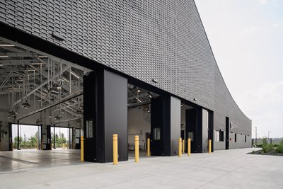 This architectural image showcases a modern industrial building with a striking black brick facade a
