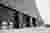 This architectural image showcases a modern industrial building with a striking black brick facade a