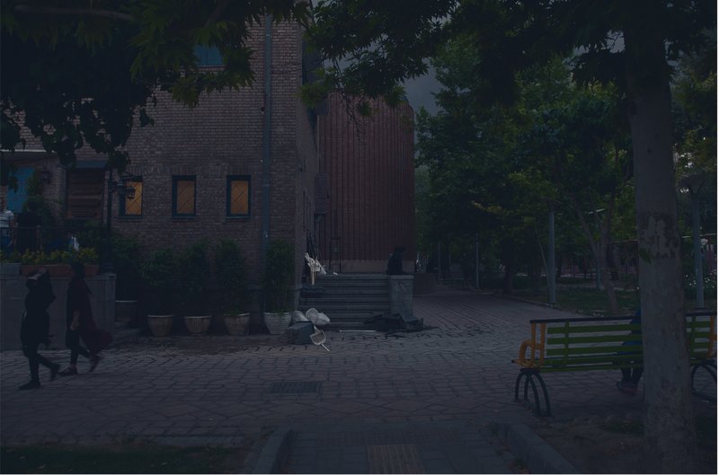 Brick building with corrugated metal extension and entrance steps visible through trees at dusk