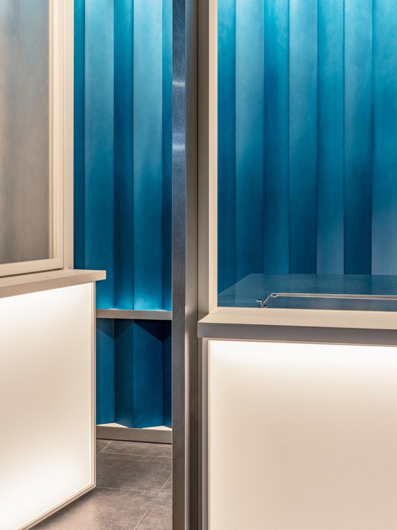 Interior view showing blue vertical fabric panels and white counter with slim metal framing