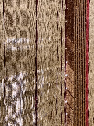 The image showcases a close-up of a woven textile with vertical lines and a rich, earthy color palet