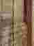 The image showcases a close-up of a woven textile with vertical lines and a rich, earthy color palet