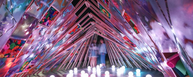 Inside the colorful and creative space of Hi Ladders High, where light, art, and architecture blend together under the night sky.