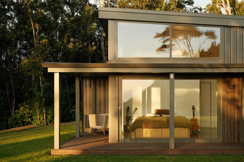 Two-storey bedroom wing with covered timber deck and full-height glazing at dusk
