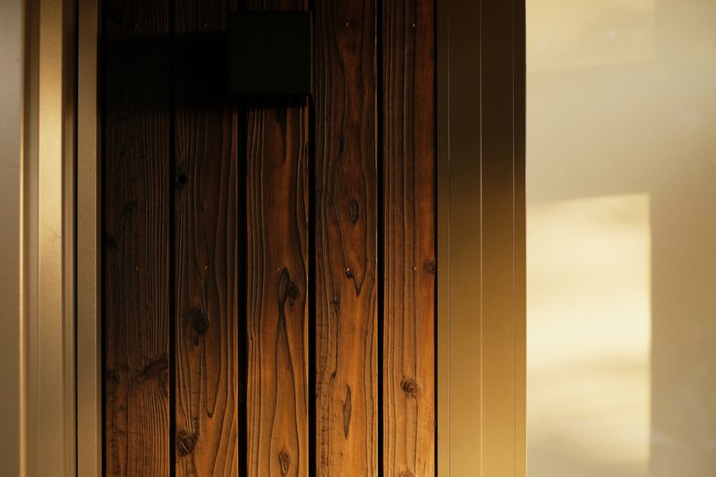 Close-up of vertical timber planking showing grain and knots with afternoon shadow on adjacent wall