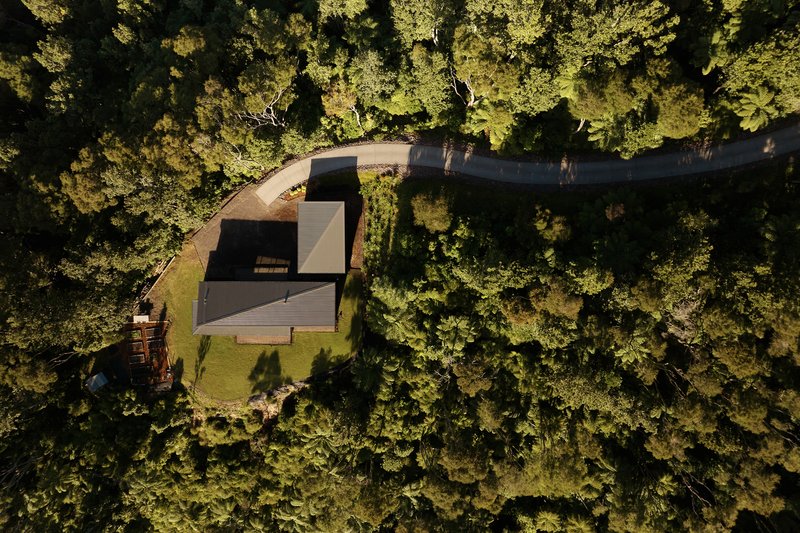 Aerial view of the angular roof surrounded by dense forest canopy in late afternoon sun