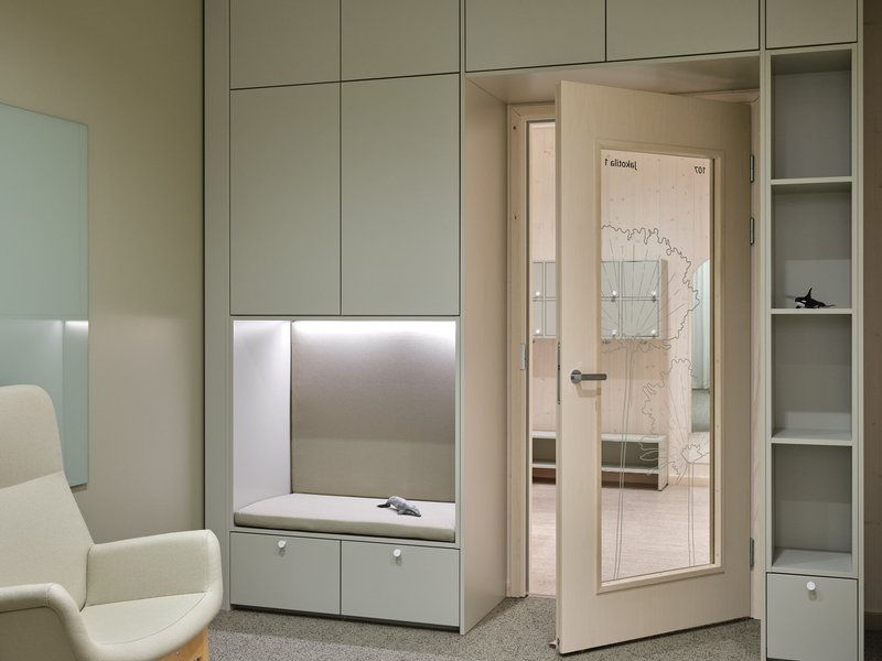 Built-in storage unit with illuminated alcove and glazed door leading to adjoining room