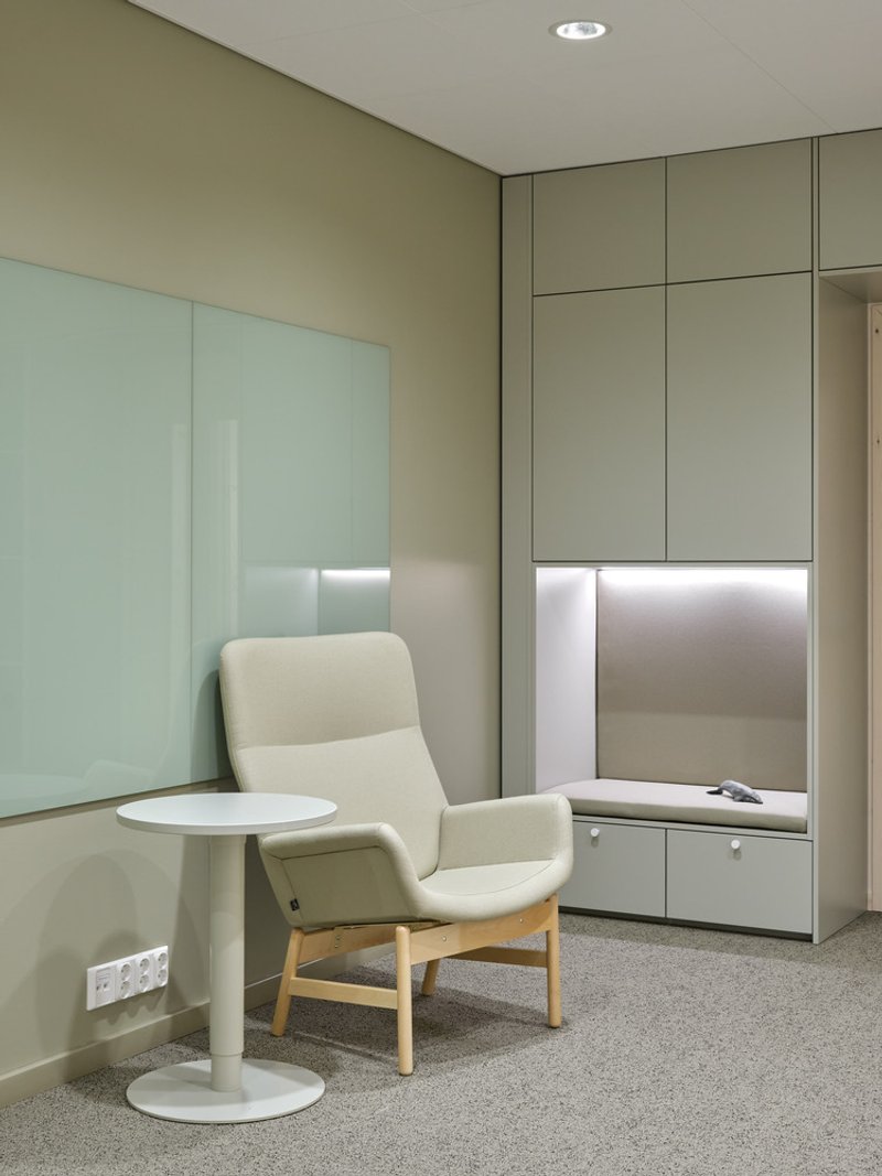 Corner seating nook with white armchair and round table beneath recessed downlight
