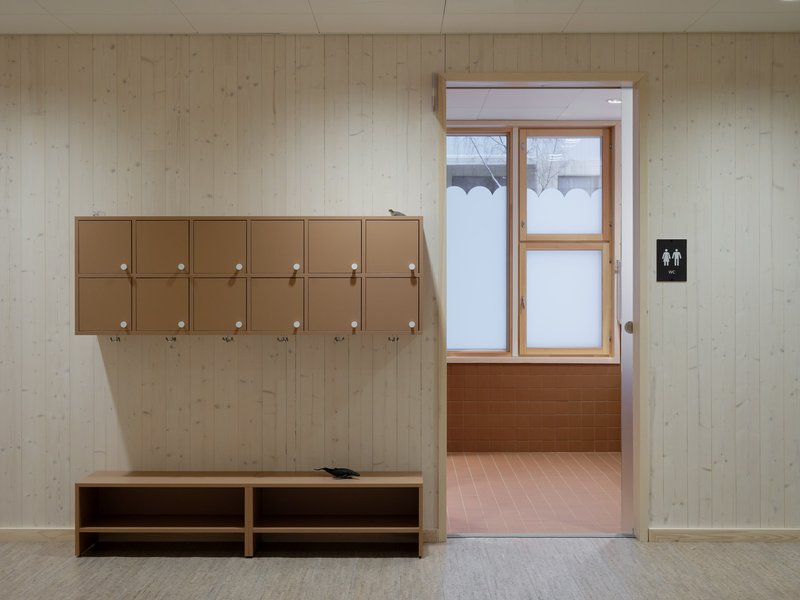 Mudroom with coat hooks and bench opening to snow-covered vestibule beyond