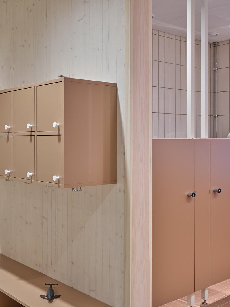Detail of tan locker units on timber wall adjacent to tiled washroom entry