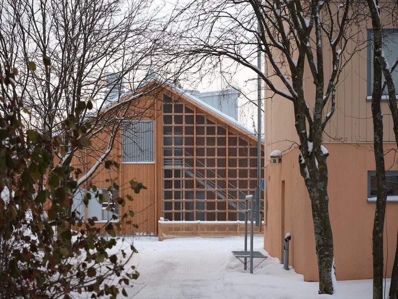 Timber gable end with gridded glass facade visible through bare winter branches and adjacent building