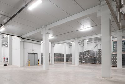 This architectural image showcases the interior of a large, modern warehouse. The space is character