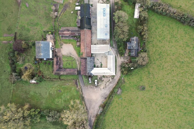 Aerial view of the cluster of buildings showing old brick structures and new white volumes arranged around a central courtyard
