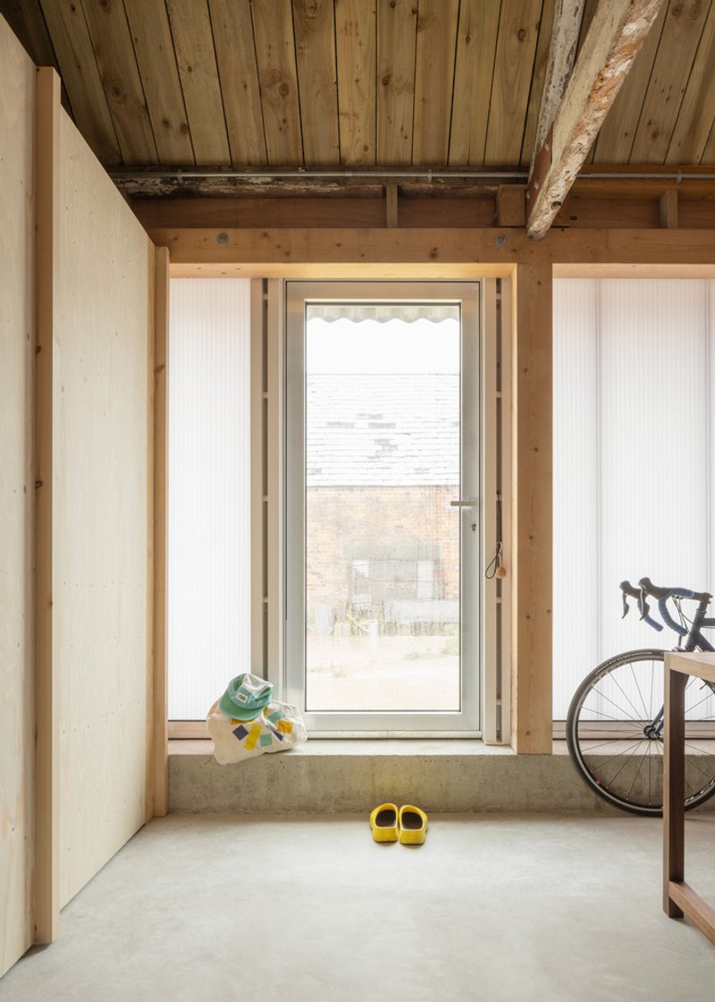 Corner window with concrete sill, children's shoes and bicycle wheel beside timber frame