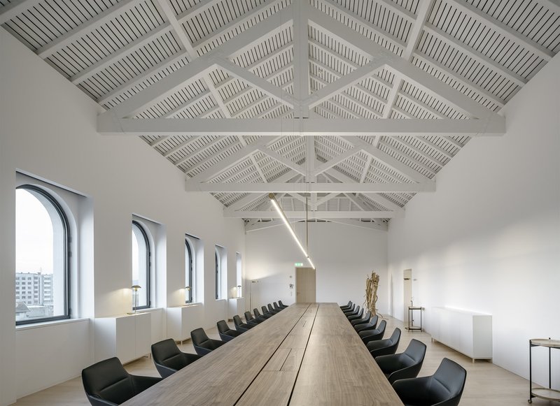 Meeting room with exposed white-painted timber roof trusses and arched windows overlooking the city
