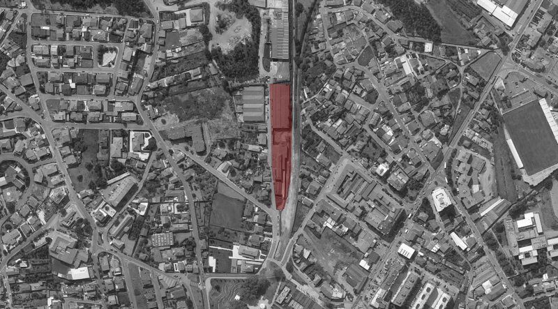 Aerial site plan highlighting the linear building footprint in red within the surrounding urban fabric