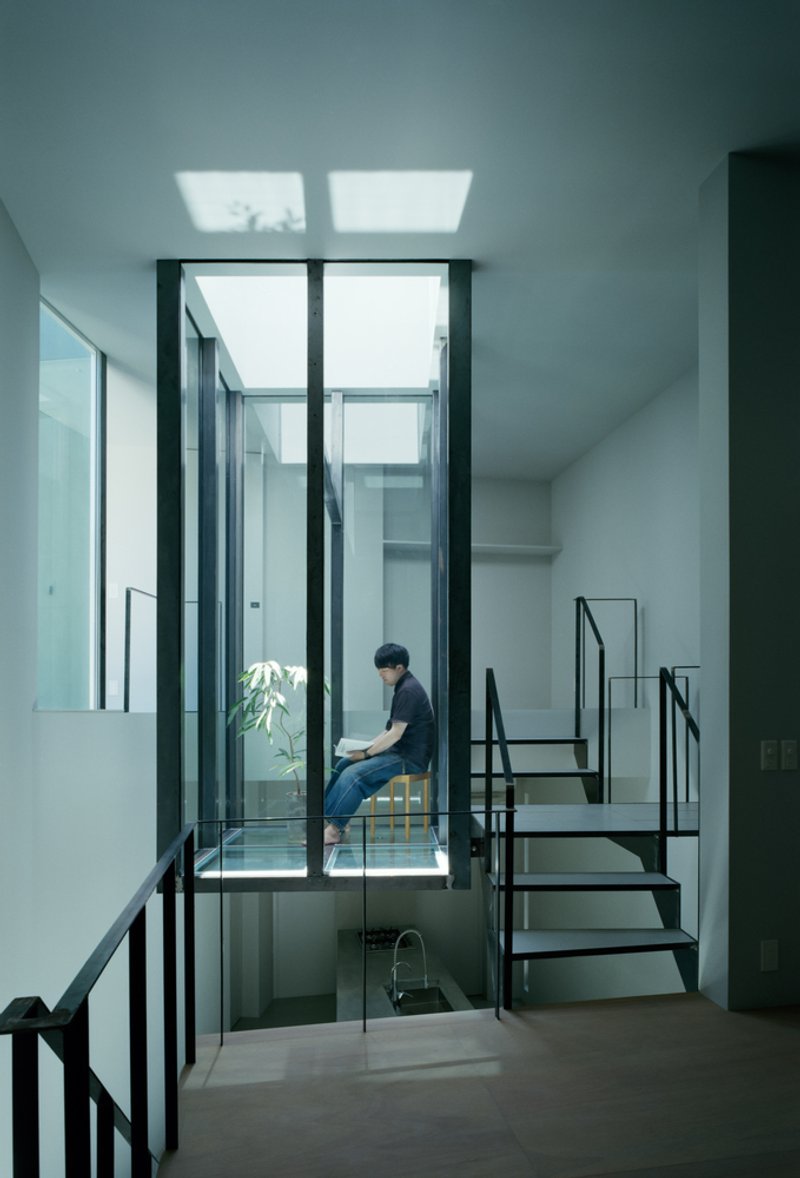 Interior view of steel staircase and glass-enclosed courtyard with person seated at window