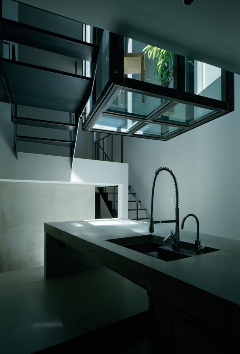 Kitchen counter looking toward steel stair and glass bridge structure in diffused daylight
