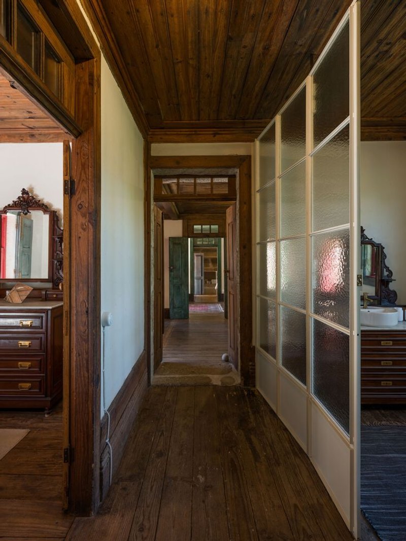Hallway with timber plank ceiling and textured glass partition wall flanked by dark wood flooring