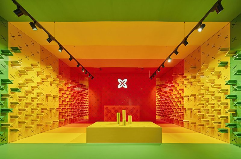 Interior retail space with pixelated wall shelving transitioning from green to yellow to red under track lighting