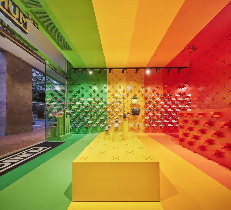Retail interior showing gradient ceiling and modular wall display system visible through storefront glazing at dusk