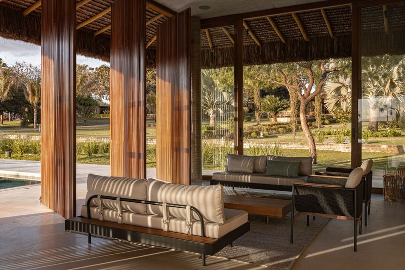 Covered lounge area with vertical timber screens filtering afternoon light from the planted exterior