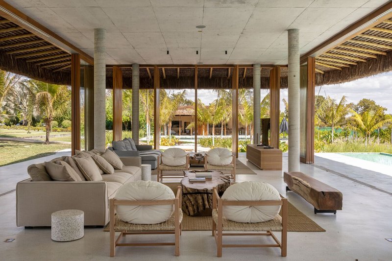 Living area beneath exposed concrete slab ceiling with cylindrical columns framing views to garden