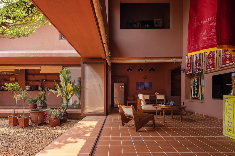 Covered terrace with terracotta tile flooring overlooking gravel courtyard with potted plants and afternoon shadows