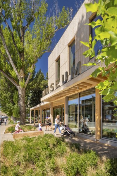 This architectural image showcases a modern museum building with a wooden facade and large glass win