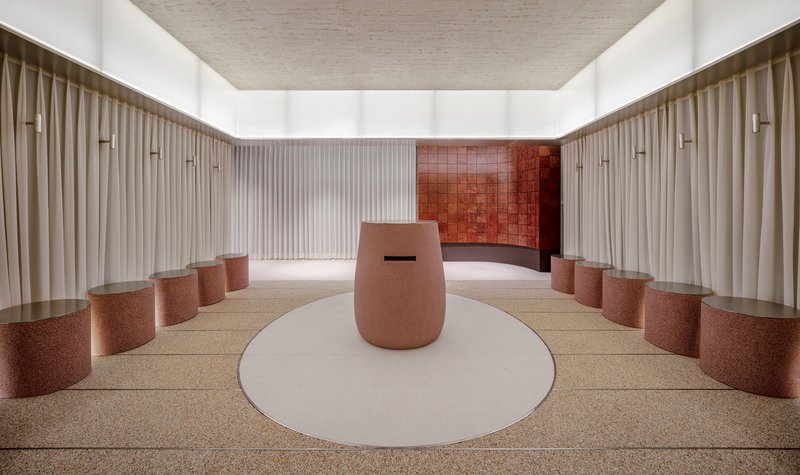 Dining hall with pink cylindrical stools flanking a white circular rug beneath a recessed ceiling