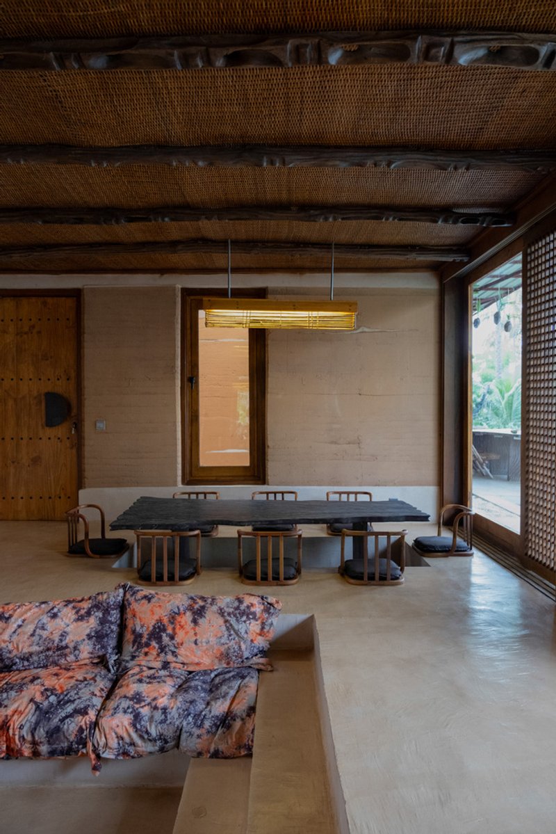Interior dining area with woven ceiling and pendant light overlooking lattice-screened opening