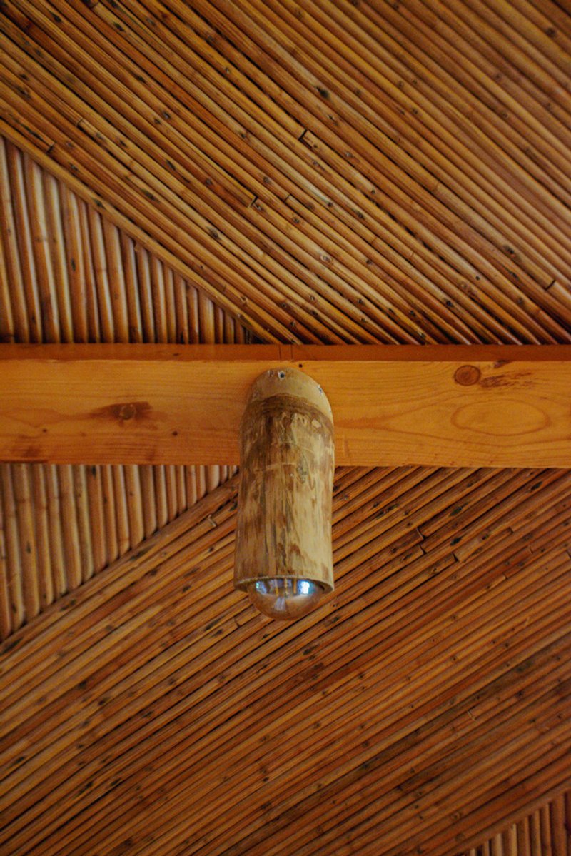 Diagonal timber slat ceiling with exposed beam and cylindrical bamboo pendant light fixture