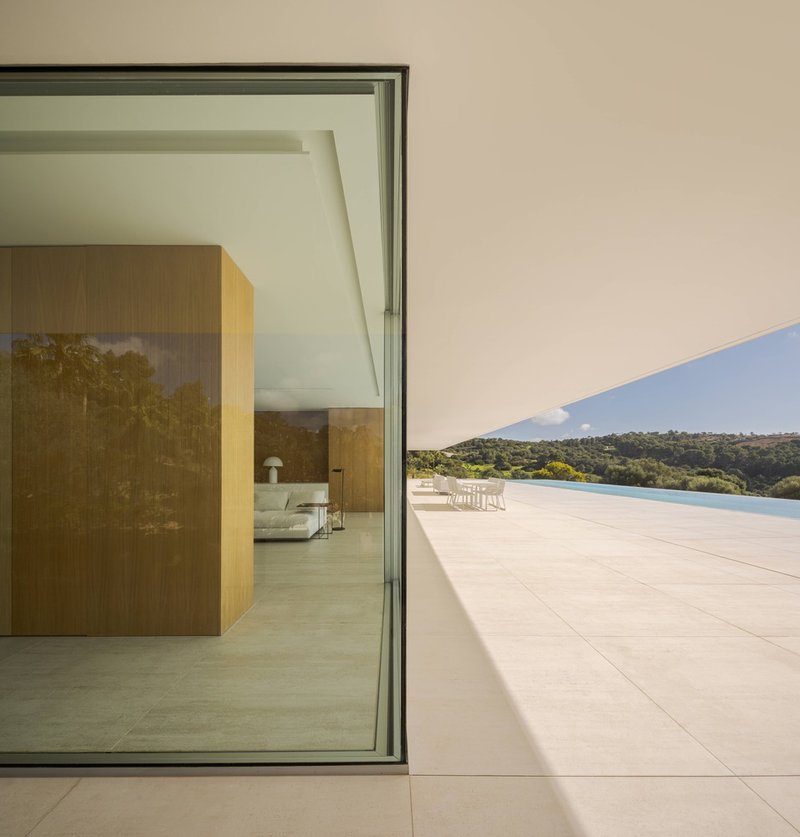 Corner threshold between interior tiled floor and exterior terrace overlooking distant forested hills and pool