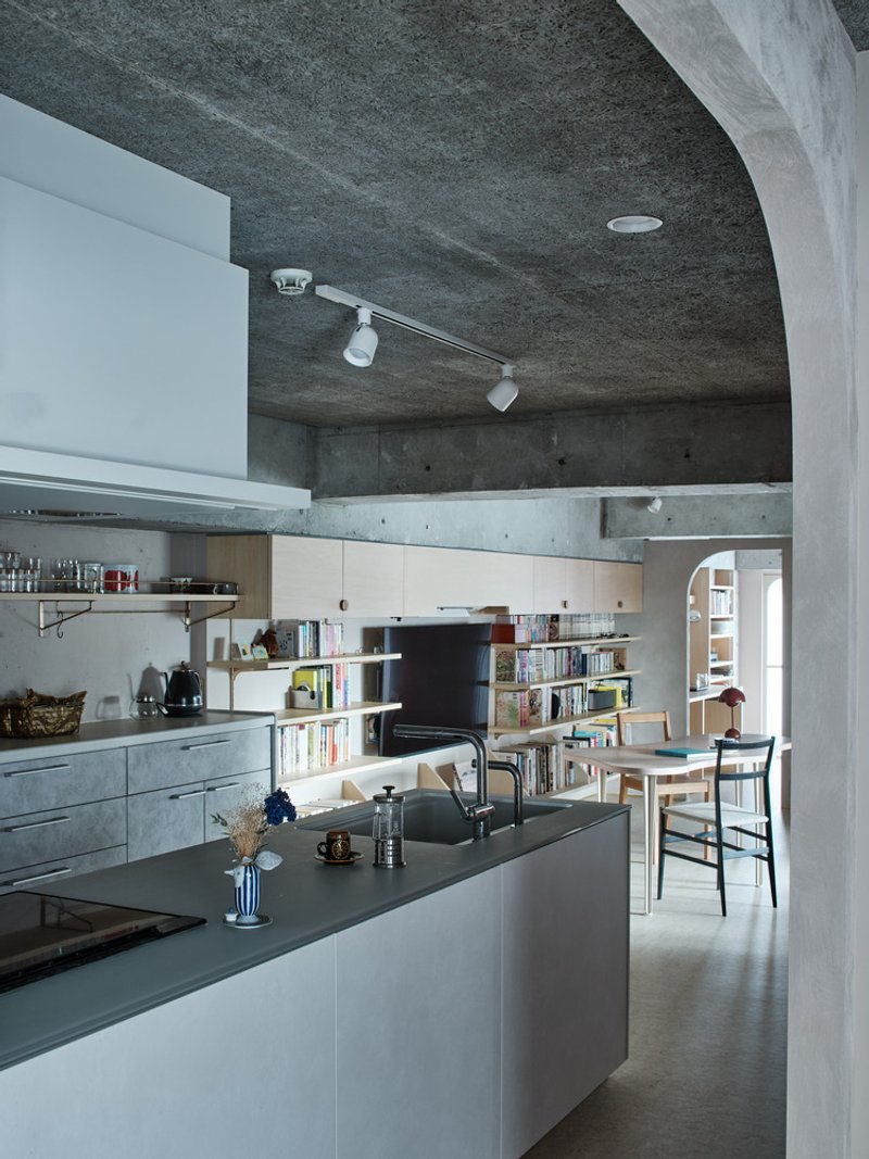 Kitchen with vaulted concrete ceiling, island countertop and open shelving under track lighting