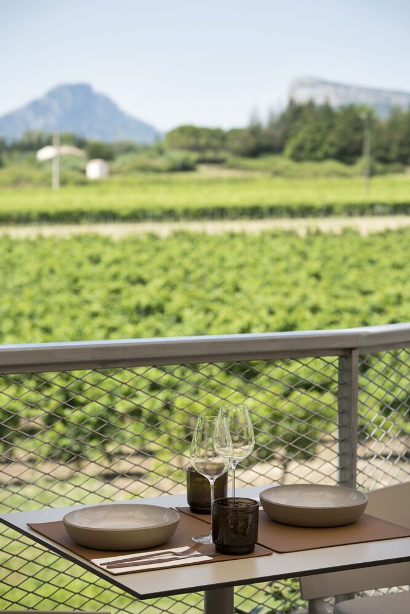 Outdoor dining table set with ceramic plates and glasses overlooking agricultural fields and distant mountains