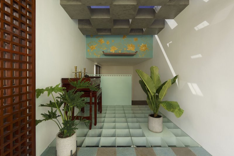 Internal courtyard with pale green tiled floor, potted tropical plants, and a painted frieze above