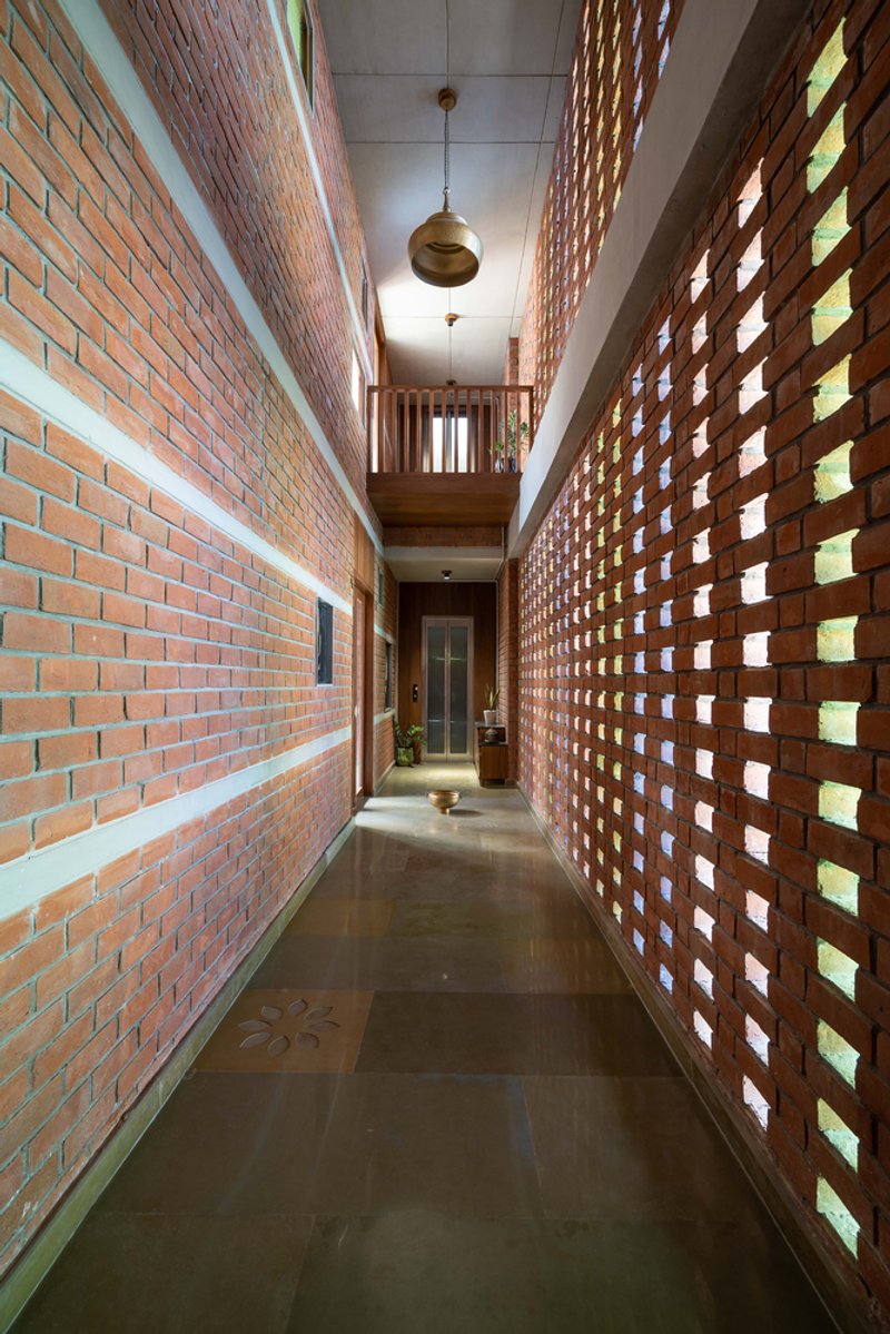 Corridor flanked by perforated brick screen wall with glass block openings filtering daylight through