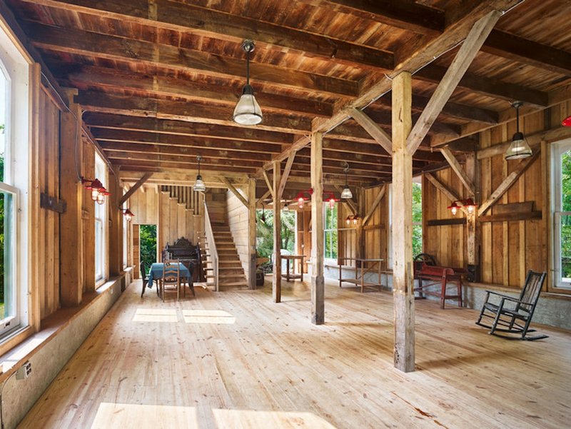 Open-plan interior with exposed timber post-and-beam structure and wide plank flooring in afternoon light