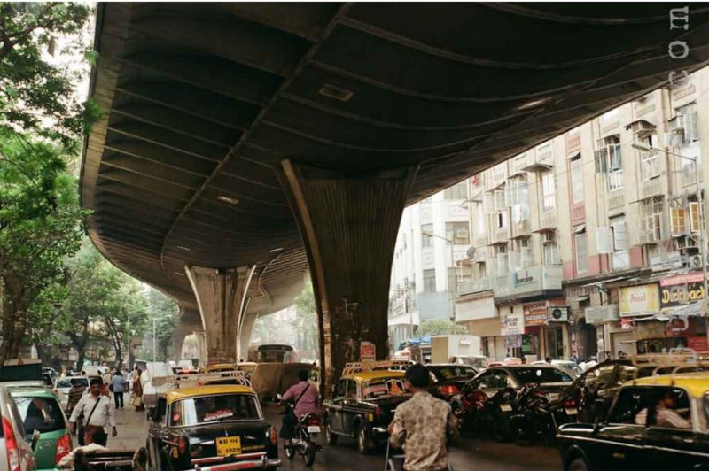 Dark, congested space beneath the flyover filled with traffic and noise.