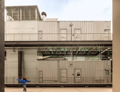 The image showcases an industrial building constructed from modular metal containers, stacked and co