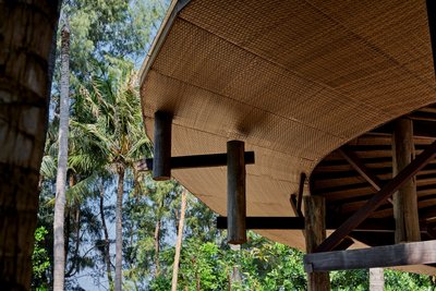 This architectural image showcases a tropical structure with a distinctive thatched roof and wooden 