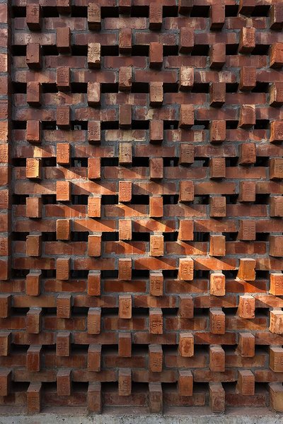 The image showcases a brick facade with a distinctive openwork pattern. The bricks are arranged in a