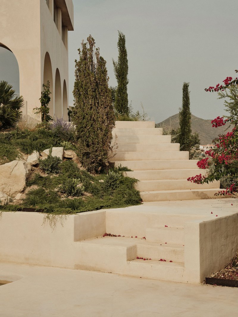 Stone staircase threading through planted beds of cypress and bougainvillea with distant mountain views